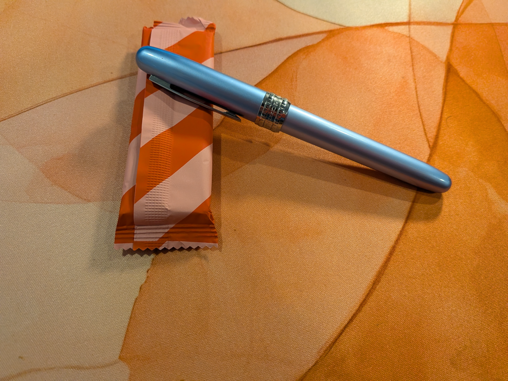 light blue fountain pen rests on a chocolate bar